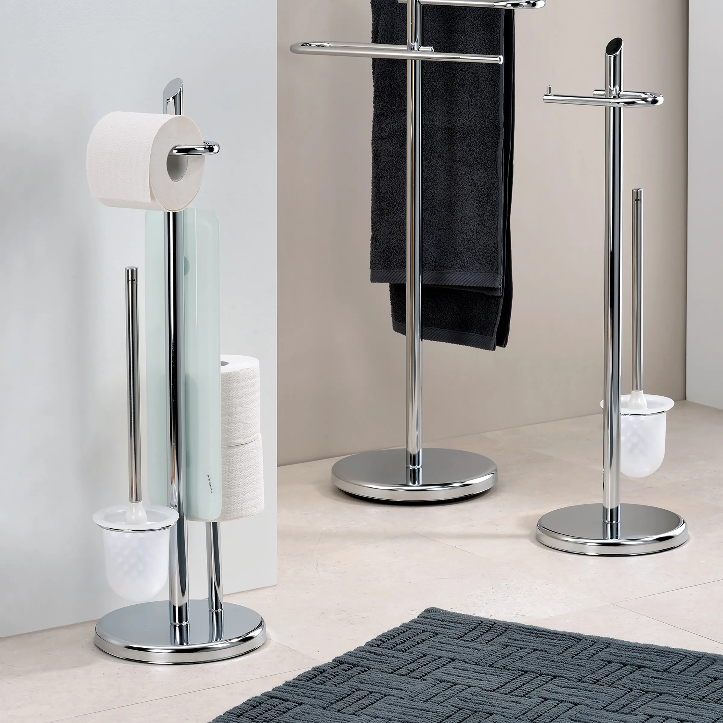 Chrom-Badezimmer-Standgarnituren mit Toilettenbürste, Toilettenpapierhalter und Handtuchhalter auf hellem Fliesenboden