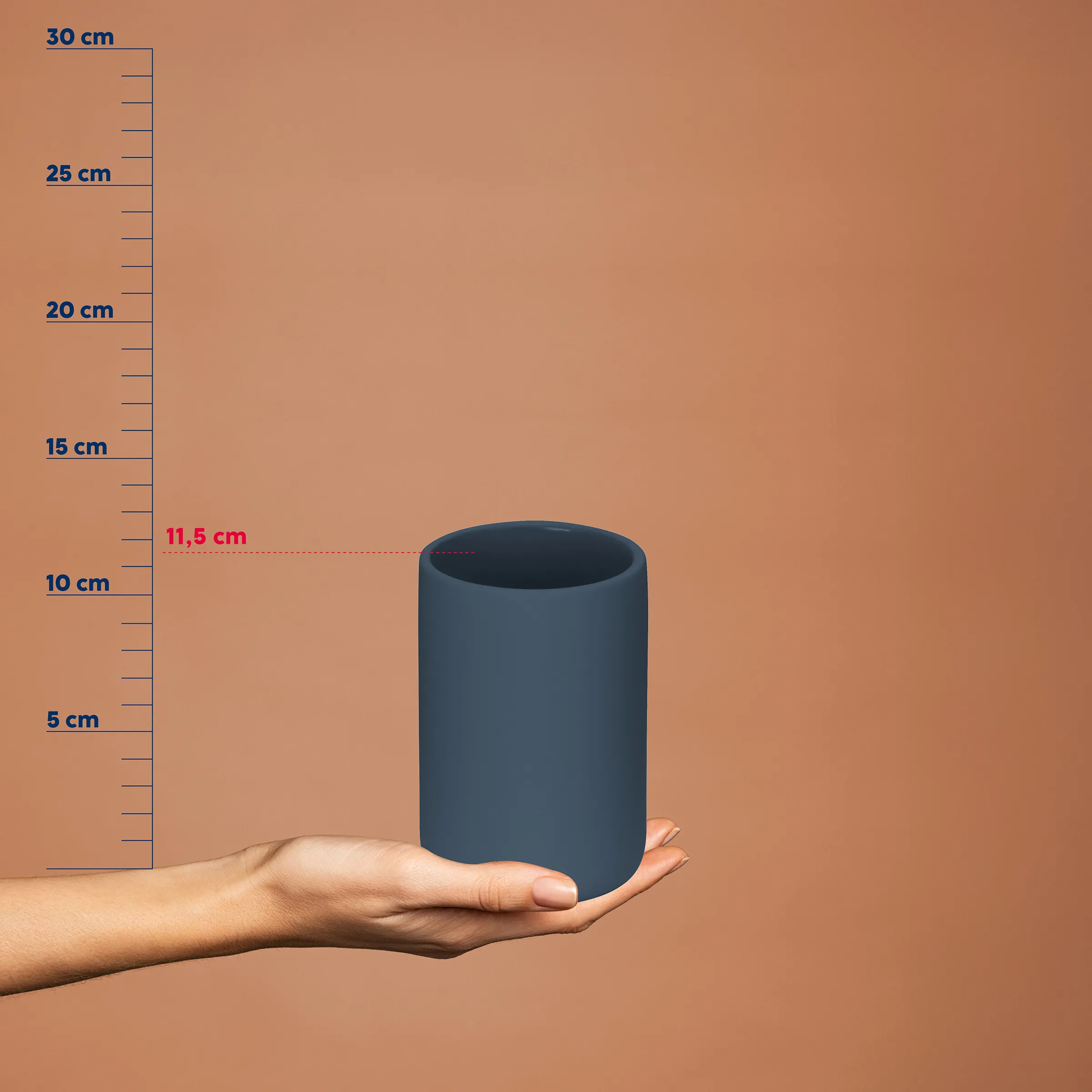 Dunkelblauer zylindrischer Behälter mit Größenvergleich auf Messskala von 5 bis 30 cm, gehalten in einer Hand