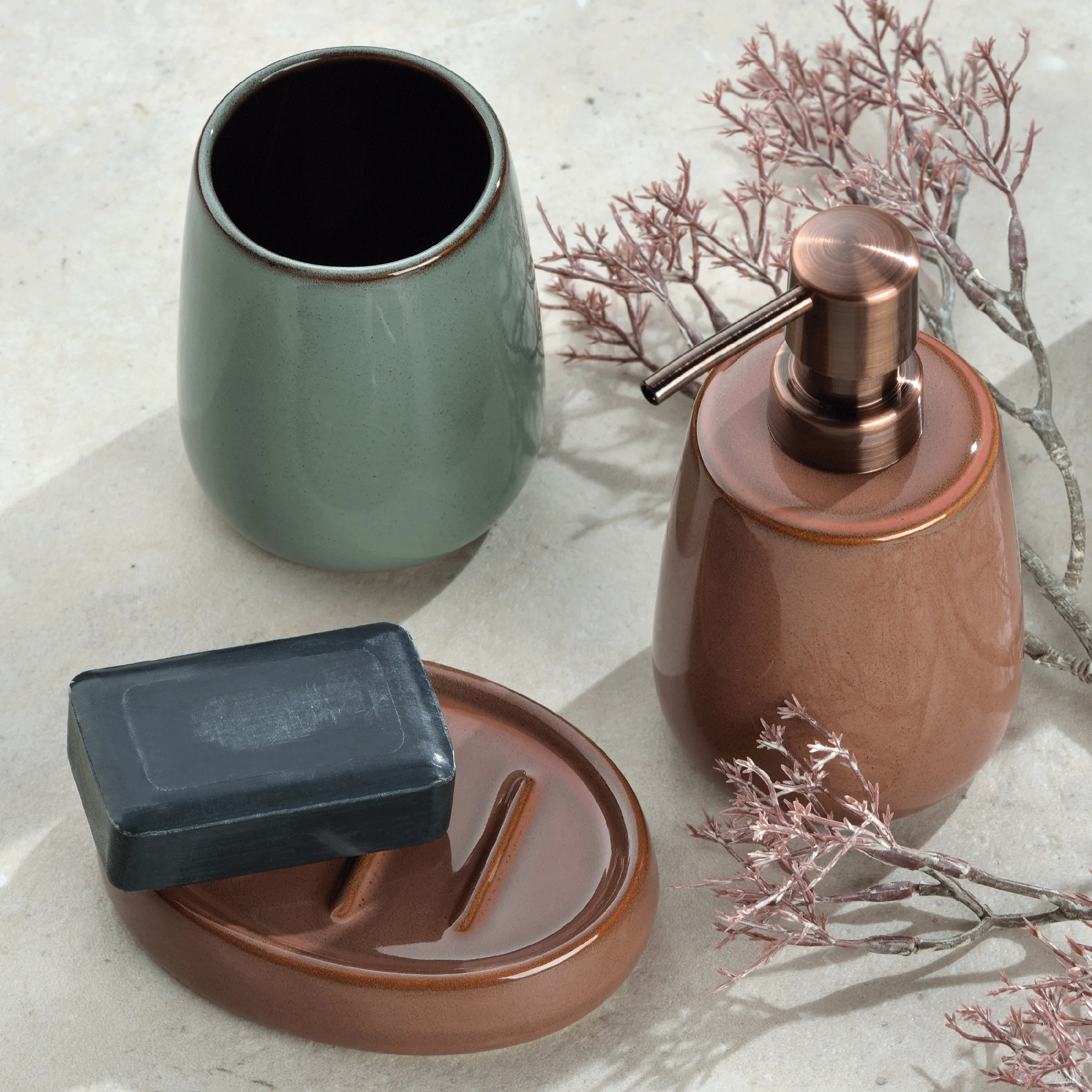 Elegantes Badezimmer-Accessoire-Set mit Seifenspender und Keramikbecher Badezimmer-Set mit türkisem Becher, braunem Seifenspender, Seifenschale und Dekozweigen auf Marmoruntergrund