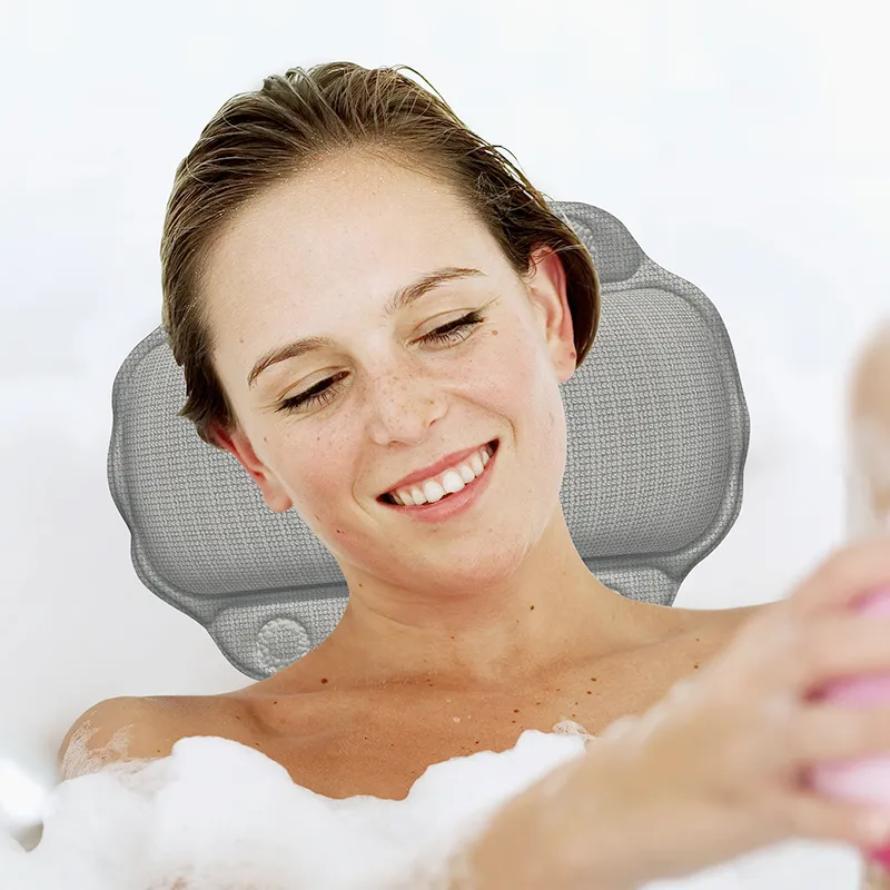 Frau in der Badewanne mit grauem Nackenkissen lächelt entspannt während sie badet