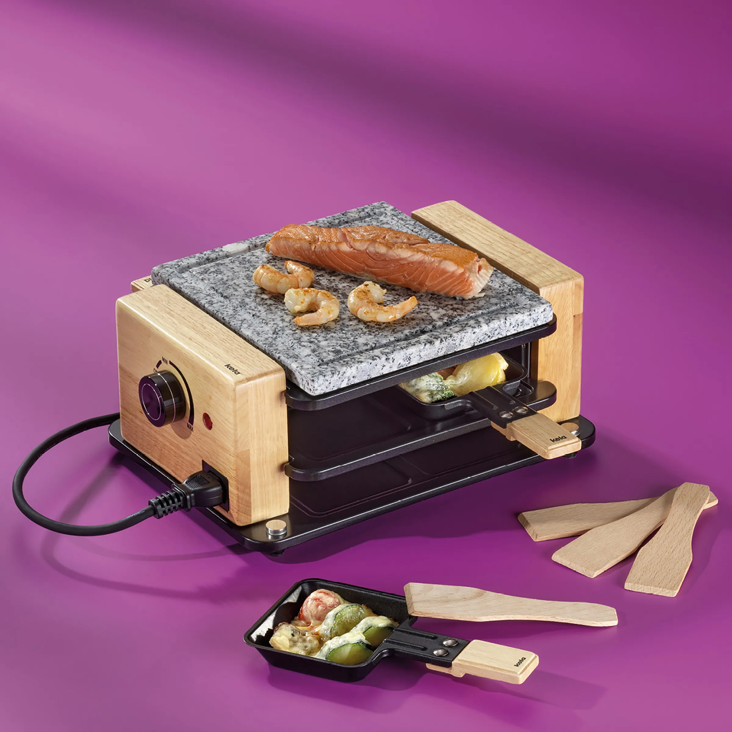 Raclette-Grill Steinplatte - Komplett Set mit Zubehör Raclette-Grill mit Steinplatte und Holzrahmen auf magentafarbenem Hintergrund, daneben zwei Raclette-Pfännchen mit Holzgriffen