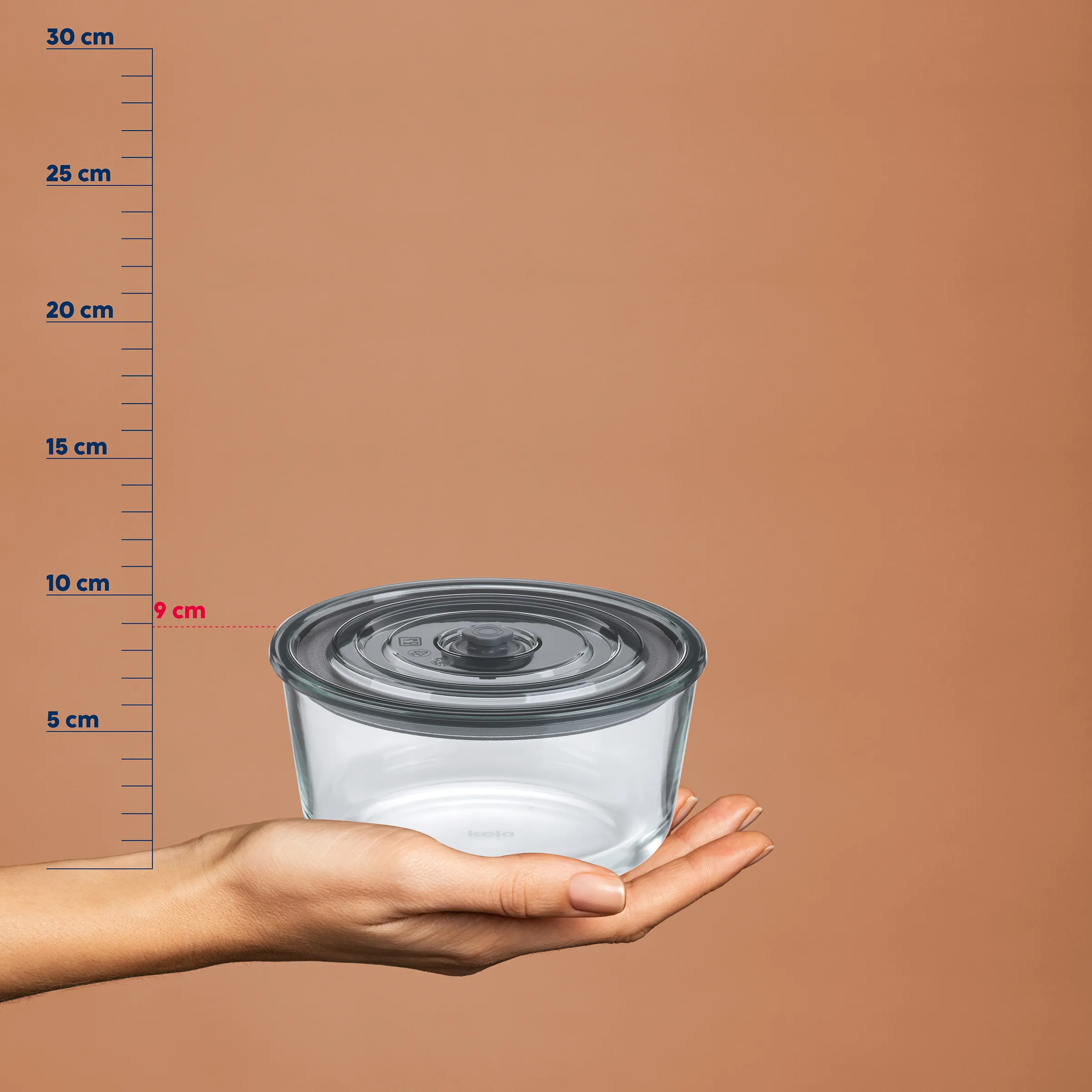 Glasschüssel mit Deckel - Aufbewahrungsbehälter Größe Transparente Glasschüssel mit grauem Deckel auf einer Hand, daneben eine Messskala von 0-30 cm mit 9 cm Höhenmarkierung
