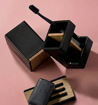 Schwarze Mascara-Set mit Wimpernbürste, offener Behälter und Applikatoren auf rosa Hintergrund