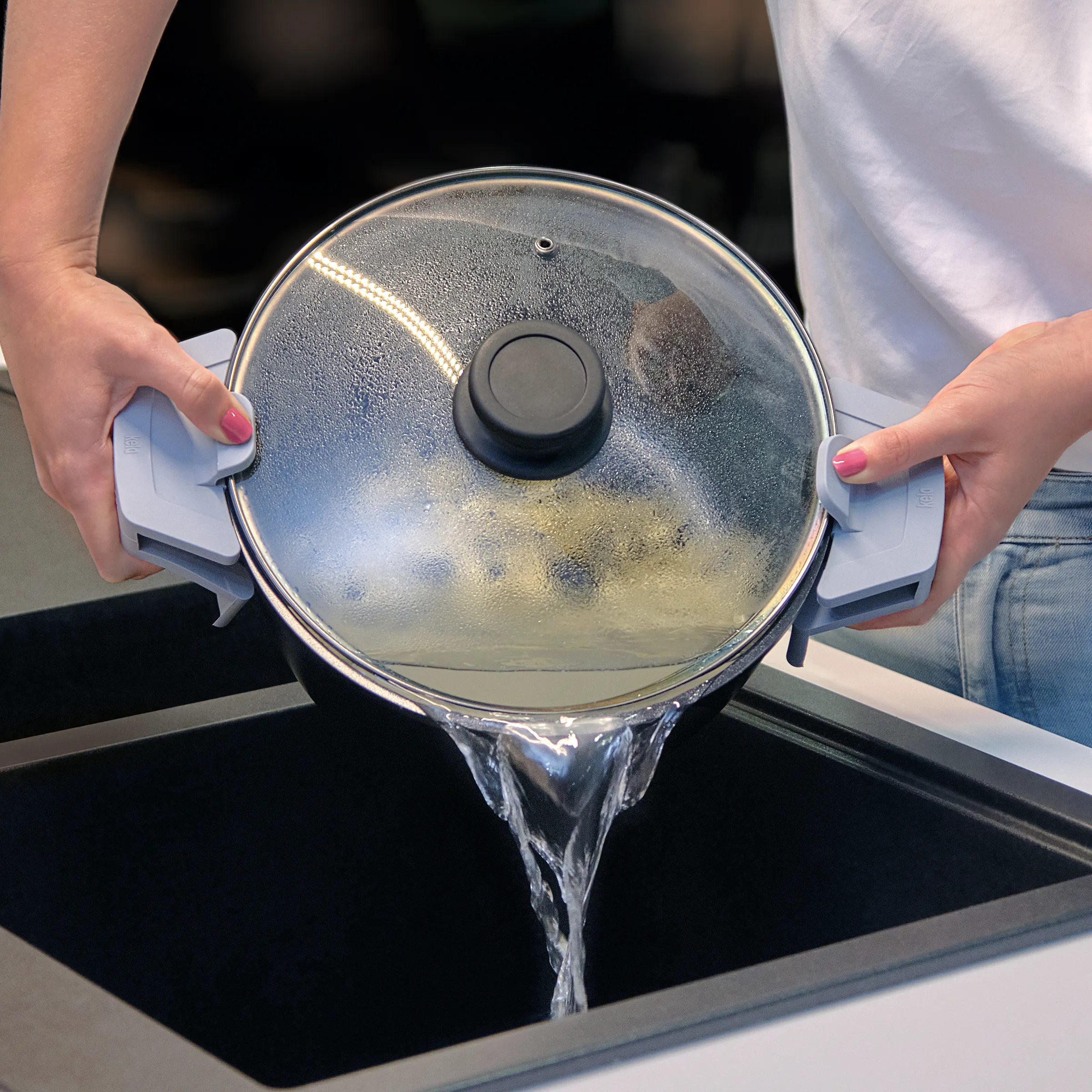 Kochtopf mit Glasdeckel und Dampfventil - Induktionsgeeignet mit Kondenswassertropfen Person hebt Topf mit Glasdeckel und Dampfablassventil vom Induktionsherd, Kondenswasser tropft vom Deckel