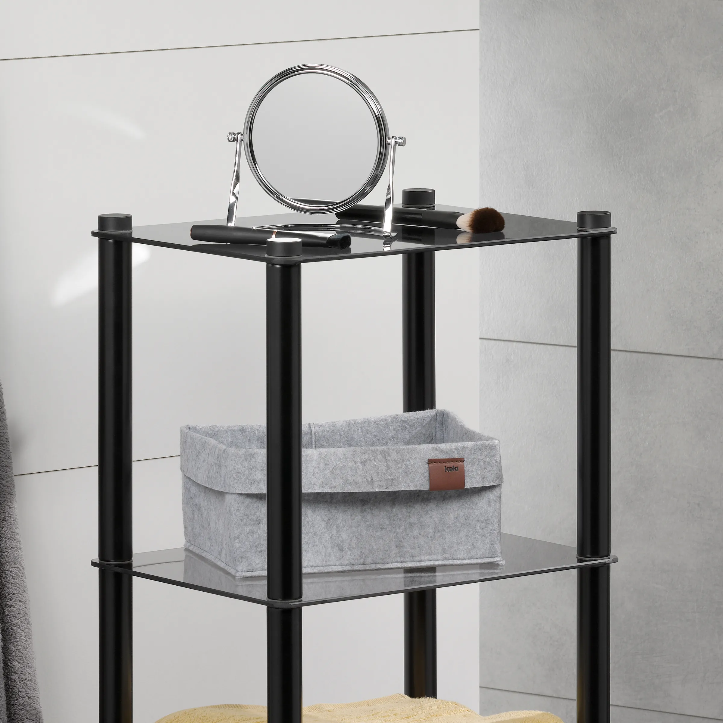 Badezimmerregal schwarz mit Spiegel und Ablage Schwarzes Badezimmerregal mit drei Glasablagen, Spiegeltuch und Kosmetikprodukten auf weißer Wand