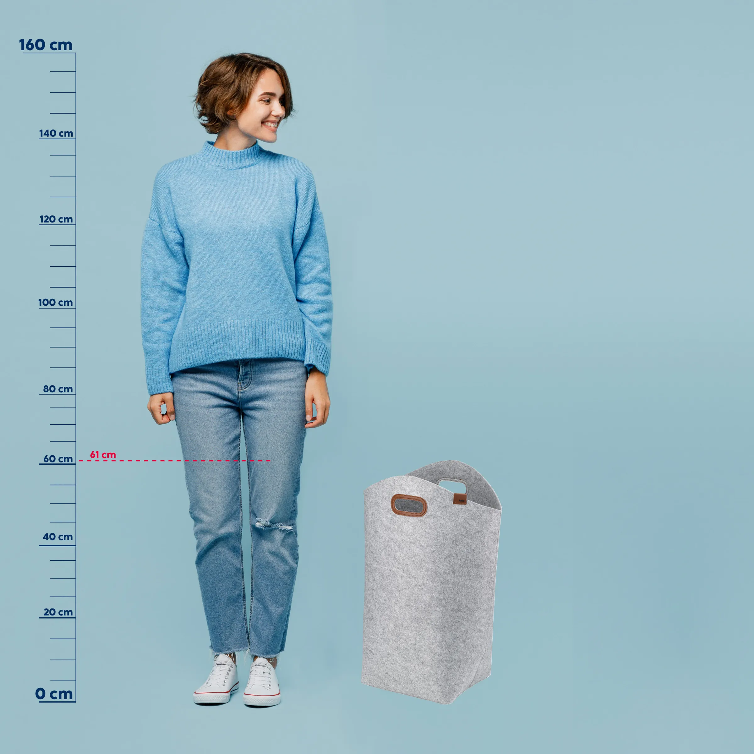 Filz-Wäschekorb 61 cm Höhe - Größenvergleich mit Maßstab Grauer Filz-Wäschekorb 61 cm hoch neben Frau mit Größenskala zur Größenreferenz auf hellblauem Hintergrund