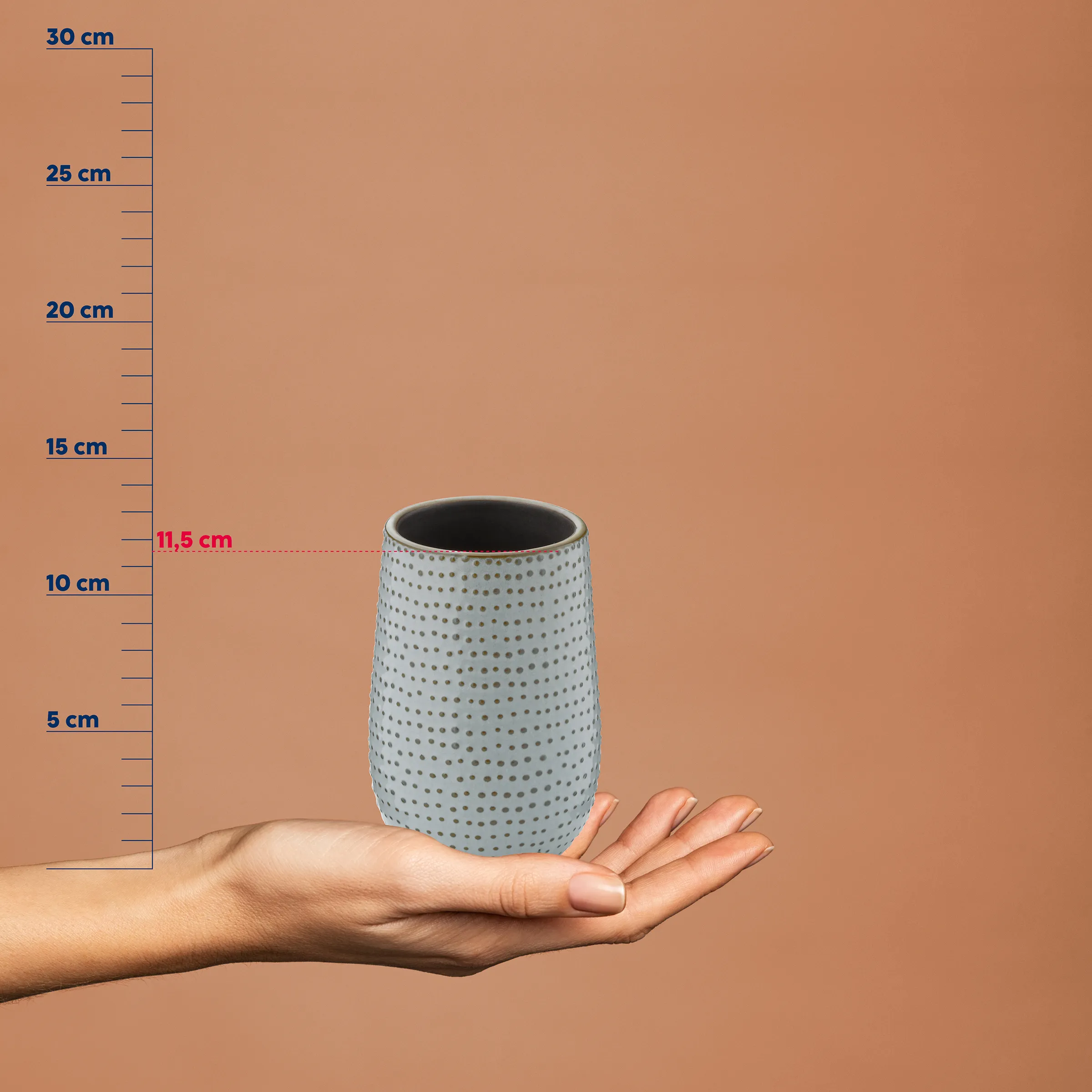 Hand hält hellblaue Keramikvase mit Punktmuster vor beigem Hintergrund mit Maßstab, Höhe 11,5 cm
