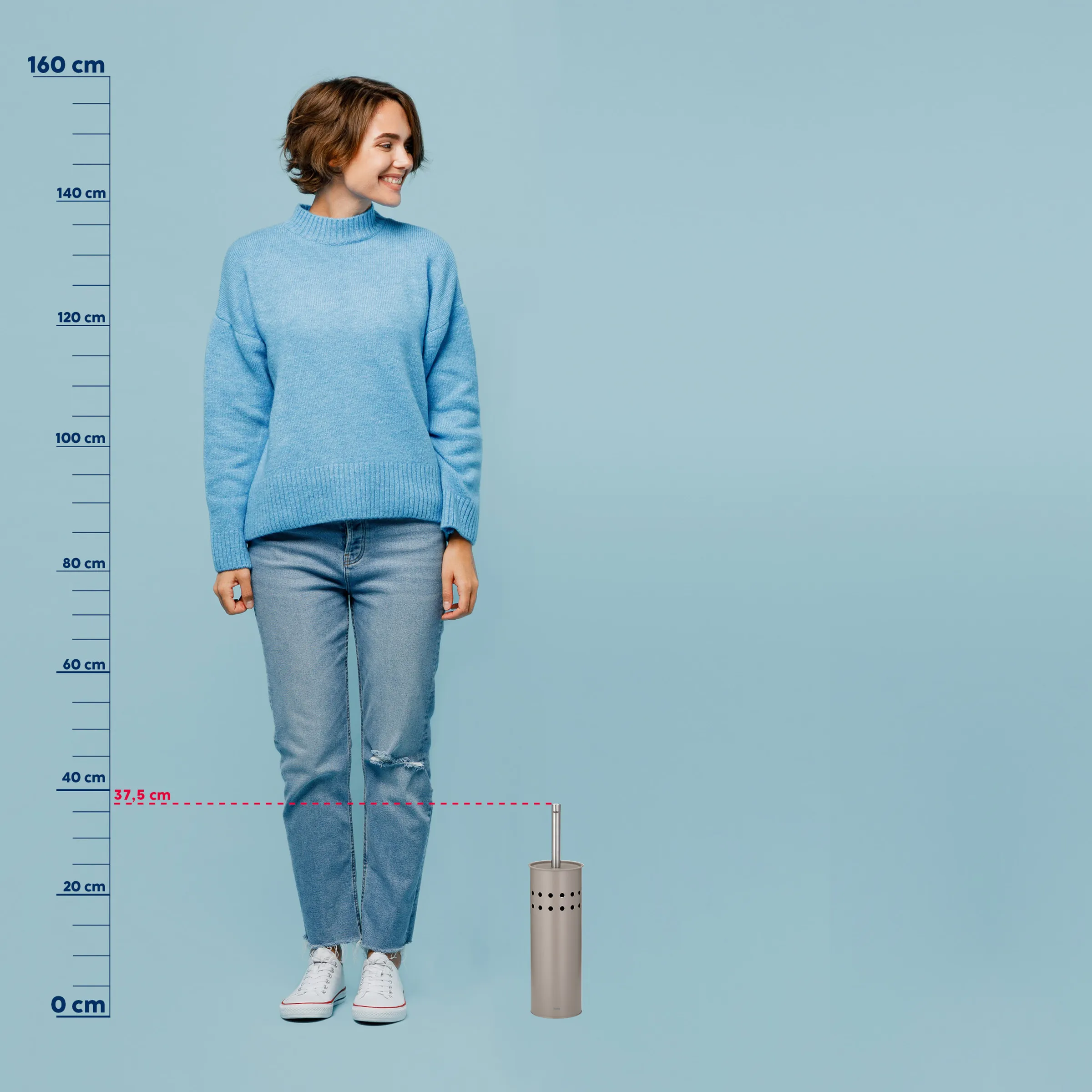 Frau in blauem Strickpullover und Jeans steht neben einem metallischen Behälter mit Größenangabe 37,5 cm