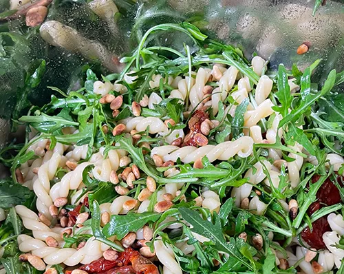Pasta mit Rucola, Hülsenfrüchten und getrockneten Tomaten in Schüssel, vegetarisches Gericht