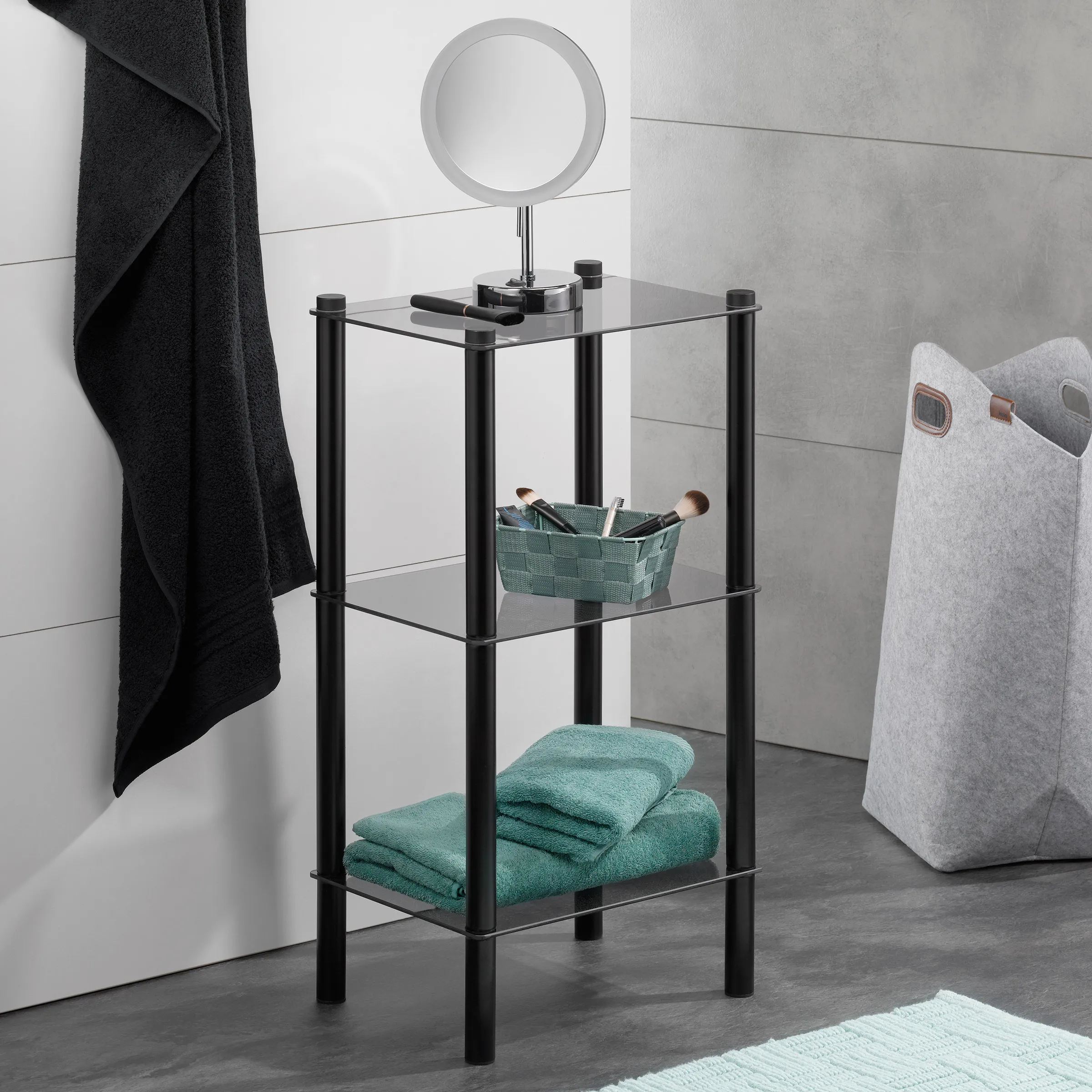 Modernes Badregal aus schwarzem Metall mit Glasböden, dekoriert mit Handtüchern, Korb und Schminkspiegel