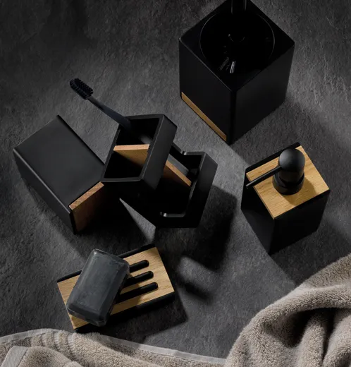 Schwarze Kosmetikprodukte mit Holzakzenten auf grauem Untergrund - Nagellack, Pinsel und Behälter