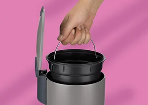 Thermobehälter Topf mit Deckel - Isolierbehälter Hand hält schwarzen Topf mit Deckel über grauem Behälter vor rosa Hintergrund