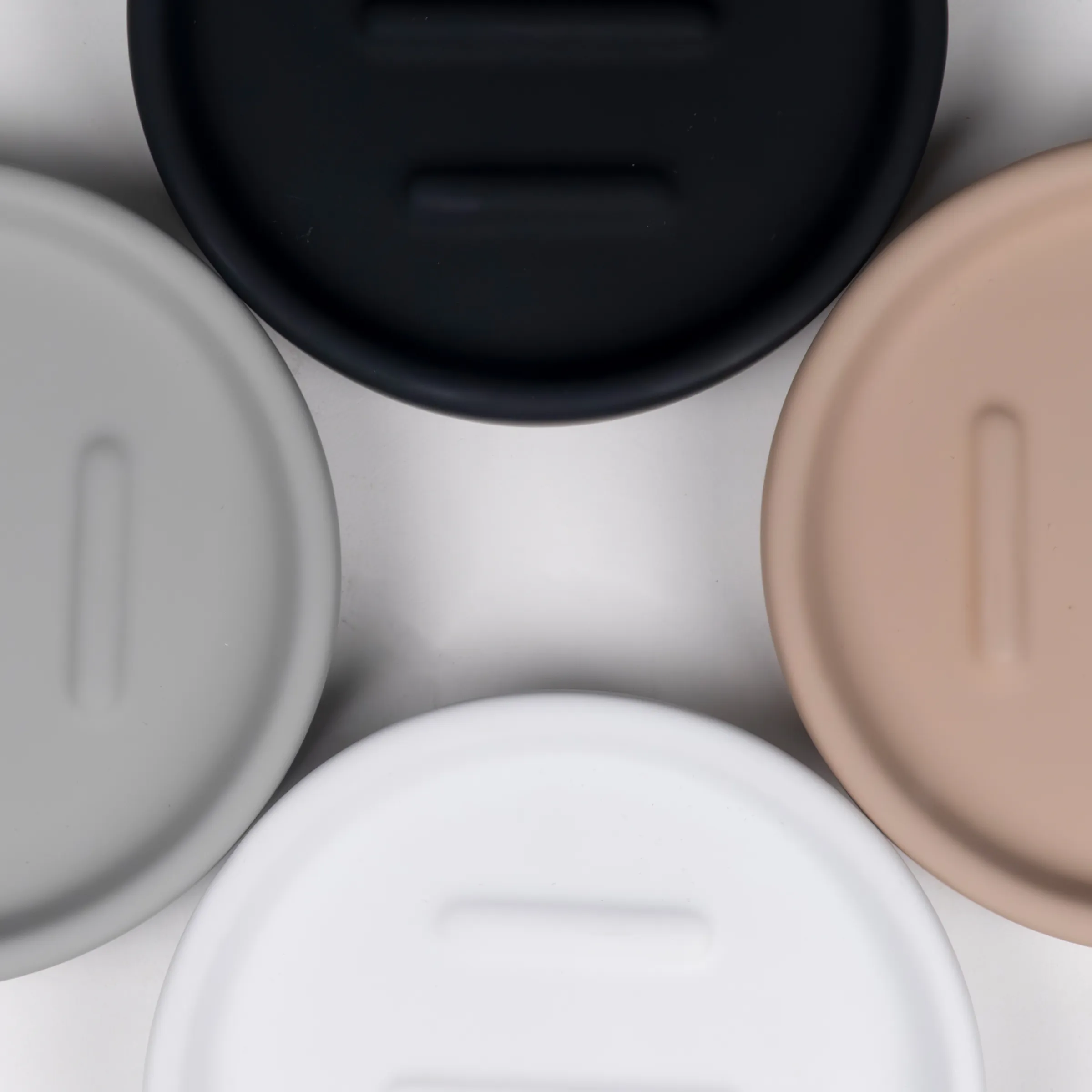 Kosmetische Cremetiegel Set - Hautpflege Produkte Overhead-Ansicht von vier kosmetischen Cremetiegel in verschiedenen Farben: Schwarz, Weiß, Grau und Beige auf hellem Hintergrund