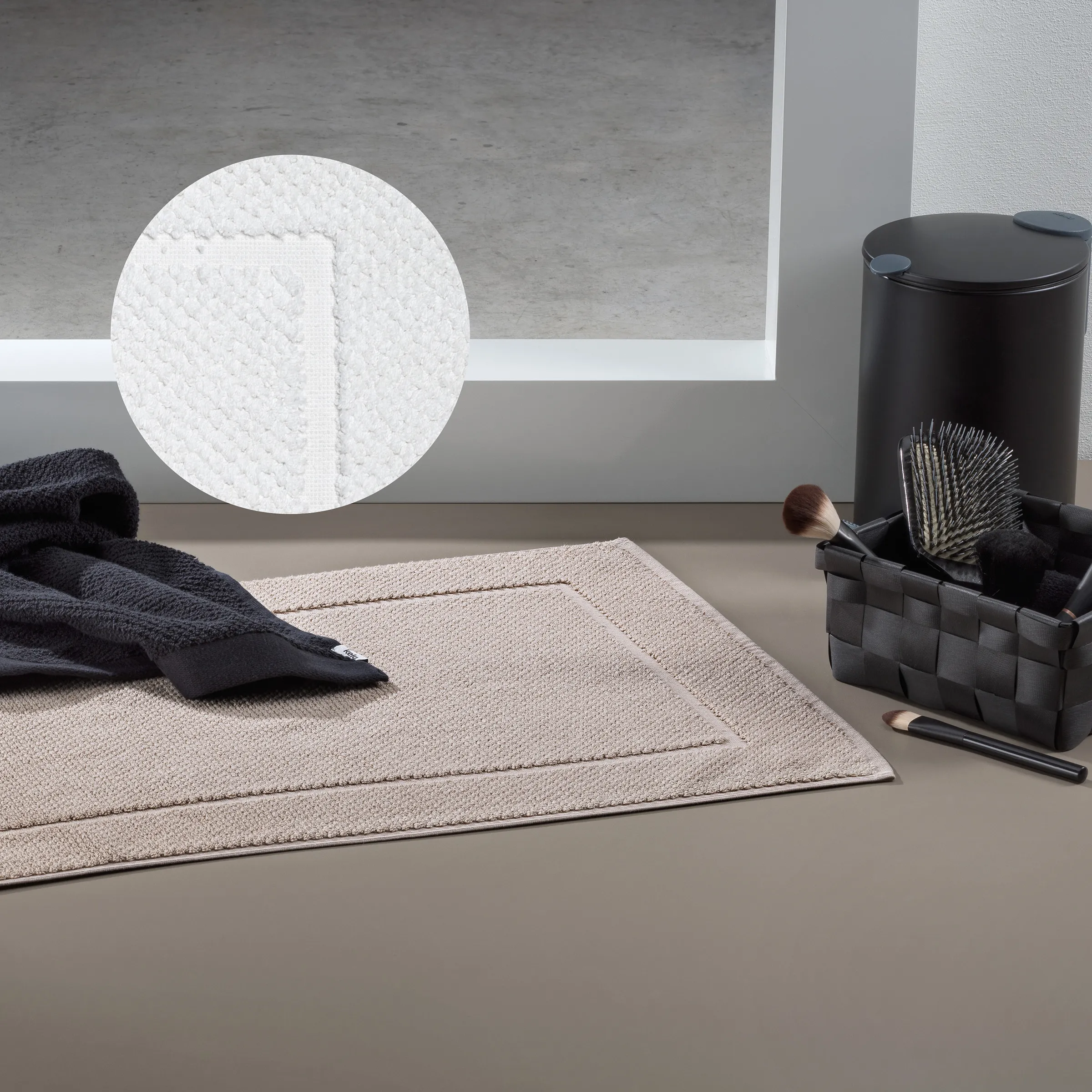 Badezimmer Accessoires Set mit Handtüchern und Kosmetikzubehör Badezimmer-Arrangement mit weißem Waschlappen, beigem Handtuch, schwarzem Behälter und Kosmetikpinseln auf grauem Untergrund