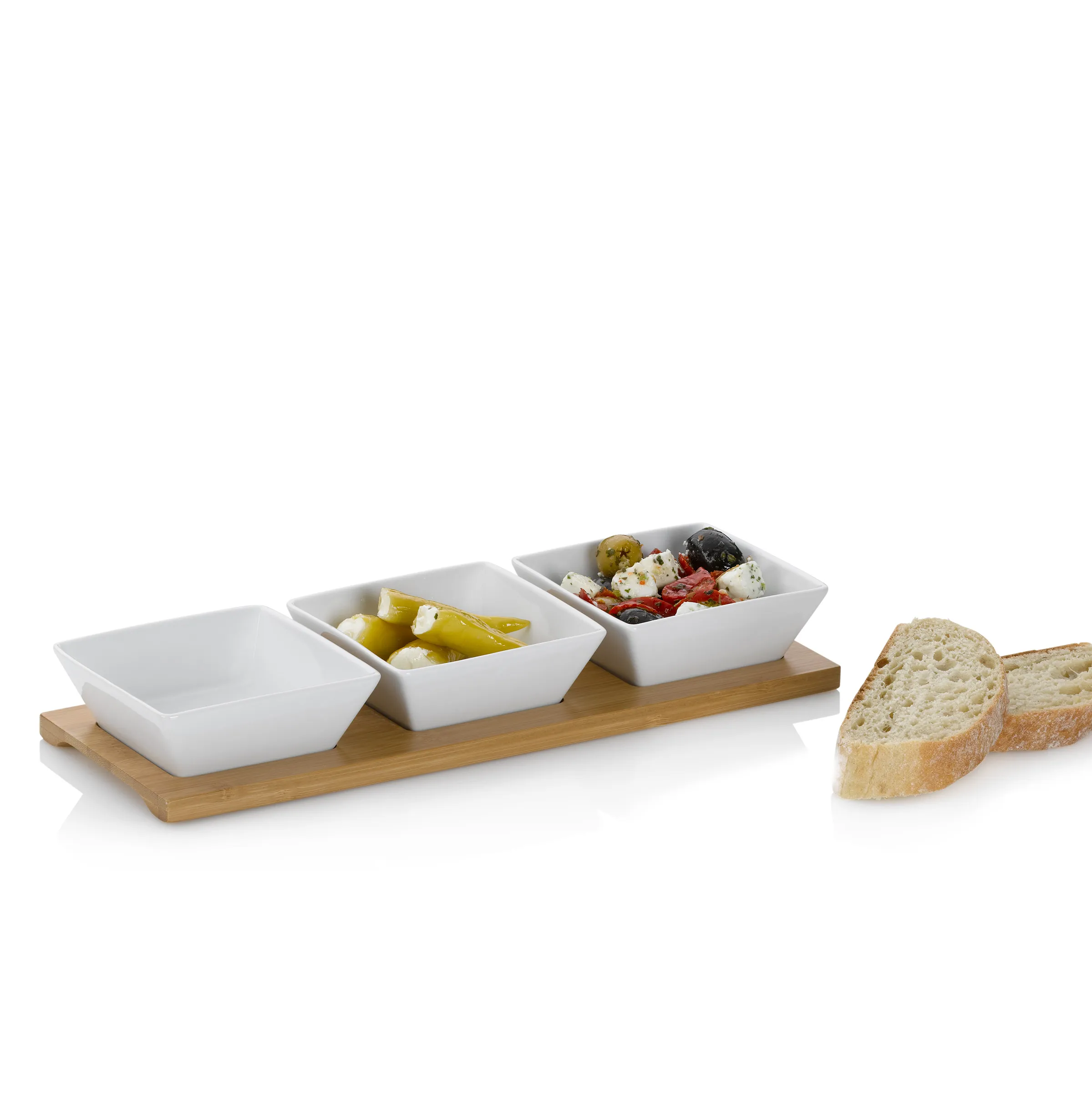 Aperitif-Servierset mit Bamboo-Tablett und Schalen Bamboo-Serviertablett mit drei weißen Schalen, gefüllt mit Oliven, Käse und eingelegtem Gemüse, daneben Brotscheiben