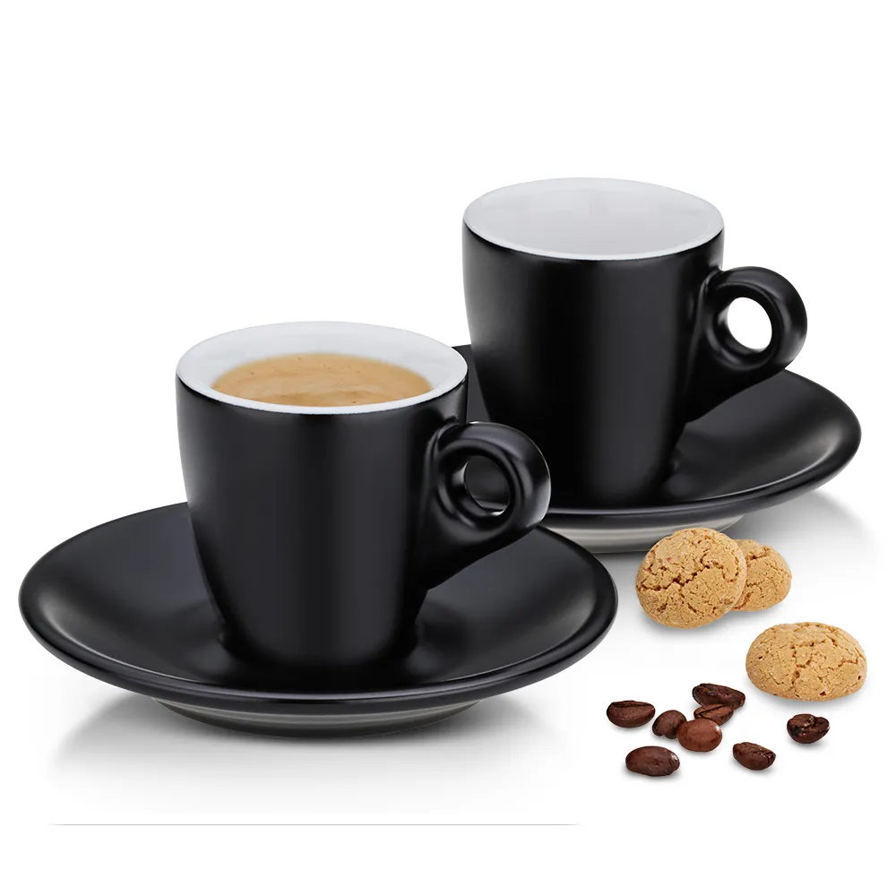 Schwarze Espressotassen Set mit Untertassen - Moderne Kaffeetassen für Espresso Zwei schwarze Espressotassen mit Untertassen, eine gefüllt mit Kaffee, daneben Kekse und Kaffeebohnen