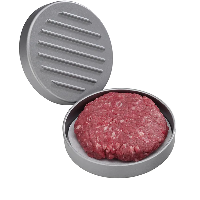 Hamburger-Presse aus Aluminium mit aufgeklapptem Deckel und rohem Hackfleisch-Patty im unteren Teil