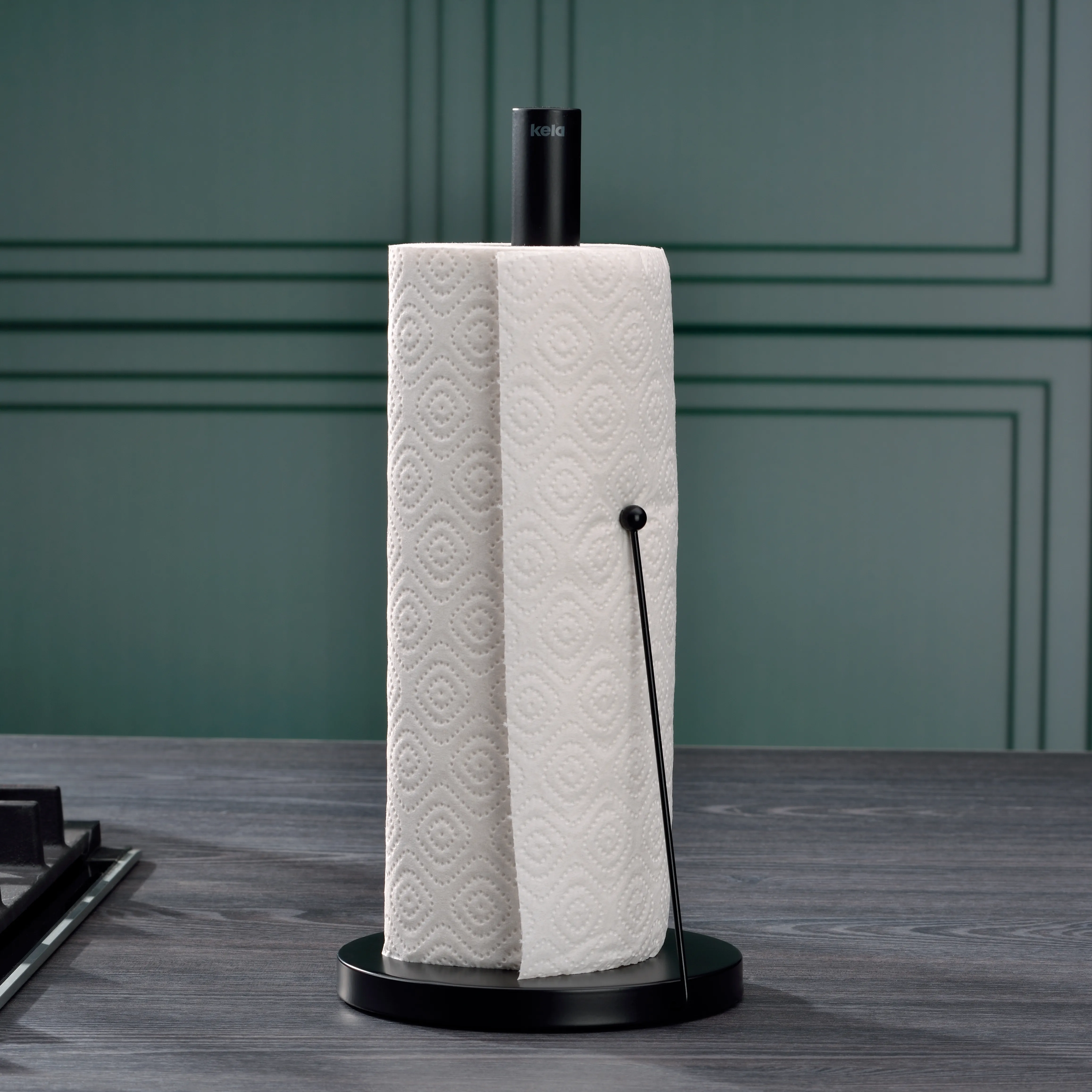 Küchenrollenhalter mit Papierrolle - moderne Küchenausstattung Schwarzer Küchenrollenhalter mit weißer Küchenrolle auf grünem Hintergrund