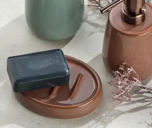 Badezimmer-Accessoires Set mit grüner Vase, kupferfarbenen Seifenspendern und Seifenschale auf Marmor