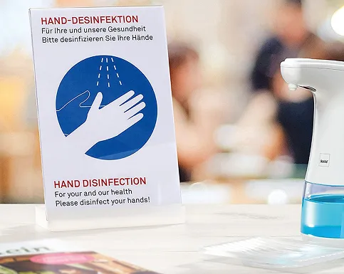 Hand Disinfection Sign - Hygiene Protection Hand disinfection instruction sign with white hand icon on blue circle and disinfectant dispenser bottle beside