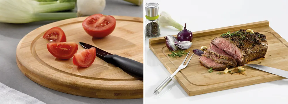 Holzschneidebretter für Küche - Rund und rechteckig mit Rillen zum Schneiden Rundes Holzschneidebrett mit Tomaten und Messer sowie gebratenes Fleisch mit Kräutern auf rechteckigem Brett