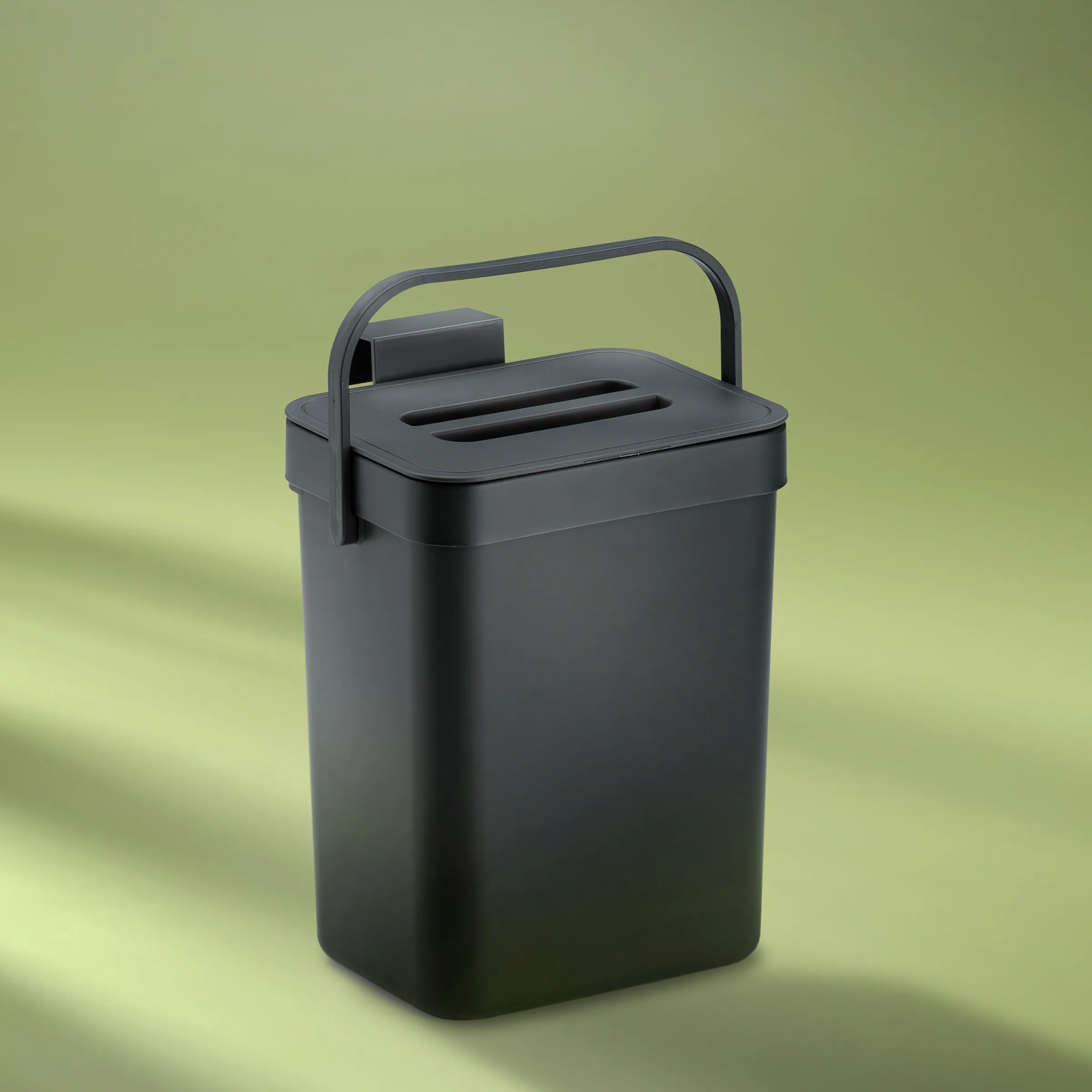 Schwarzer Papierkorbcontainer mit Griff und Schlitzöffnung auf gelbgrünem Hintergrund