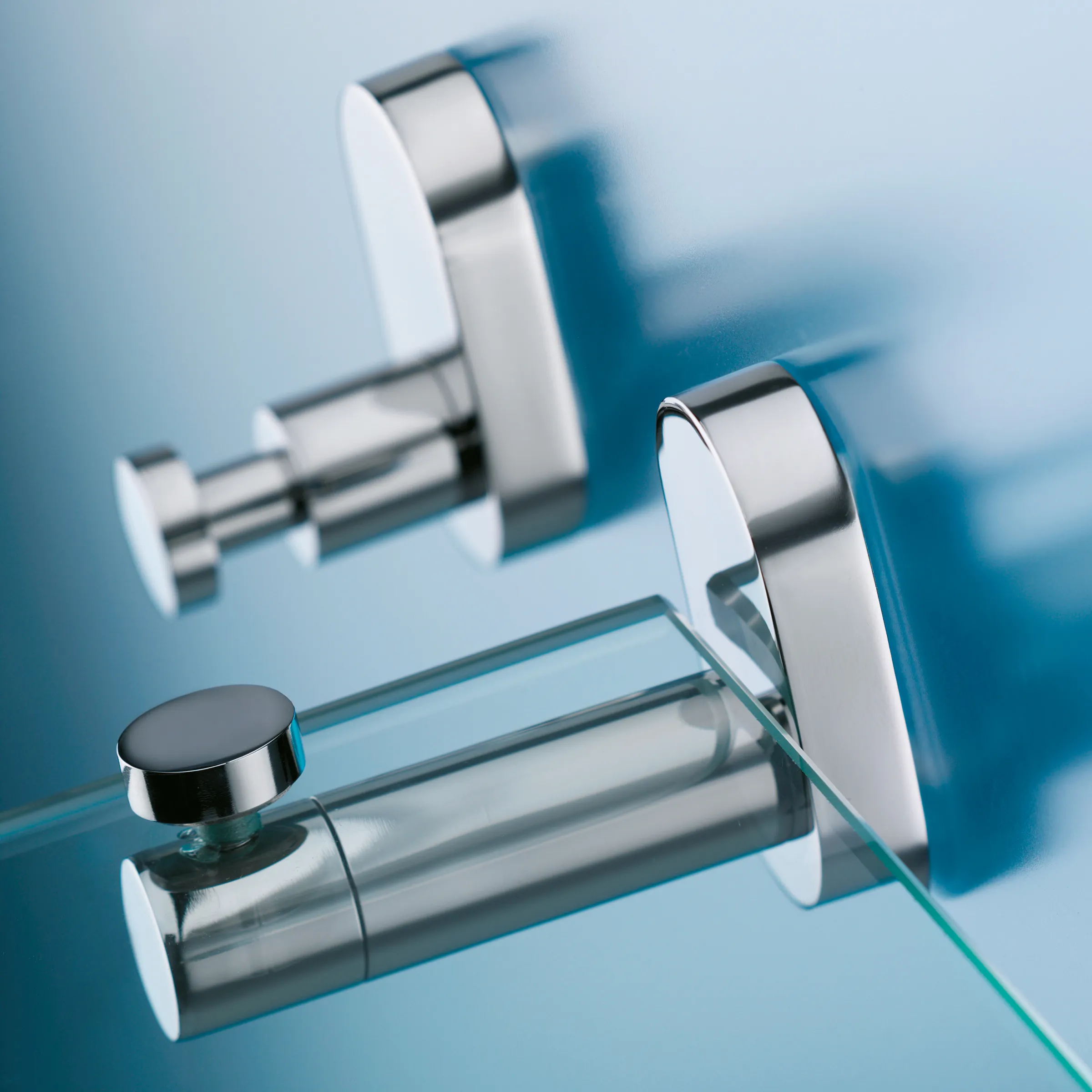 Moderne Badarmatur mit glänzenden Chrom- und Weiß-Elementen auf blauem Glas-Hintergrund mit Spiegelbild