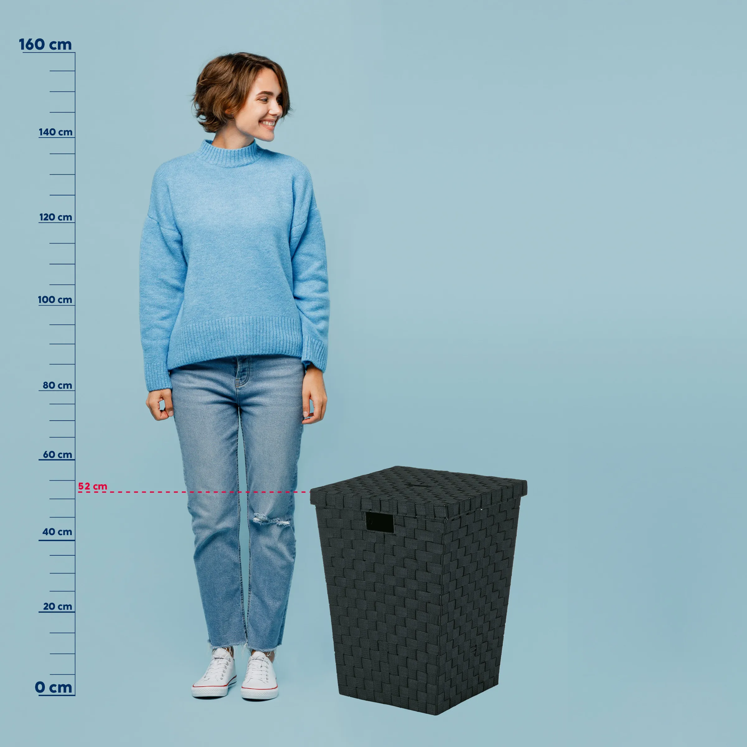 Woven Wäschekorb - Schwarzer Aufbewahrungskorb mit Größenangabe Frau in blauem Rollkragenpullover und Jeans neben schwarzem Woven-Wäschekorb mit Größenvergleich