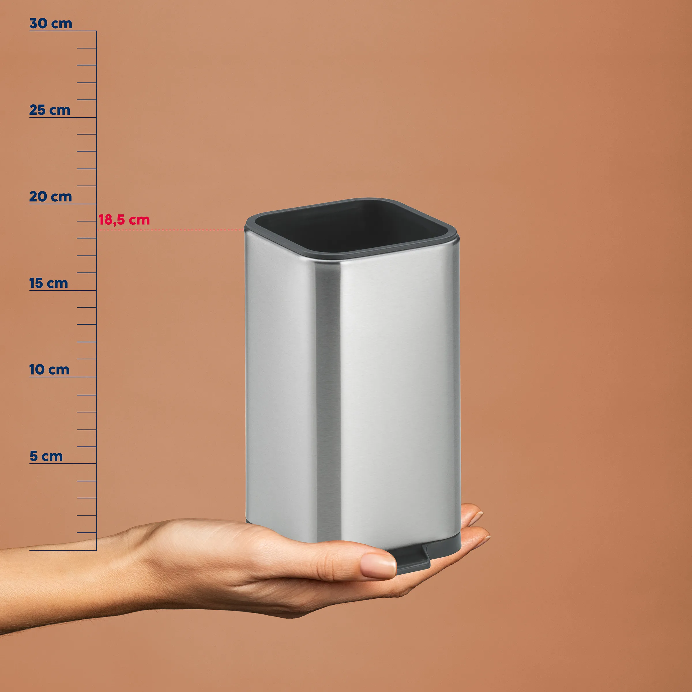 Tragbarer Bluetooth Lautsprecher kompakt Silberner tragbarer Bluetooth-Lautsprecher mit schwarzem Netz, auf Handsfläche präsentiert, neben Größenvergleichsskala