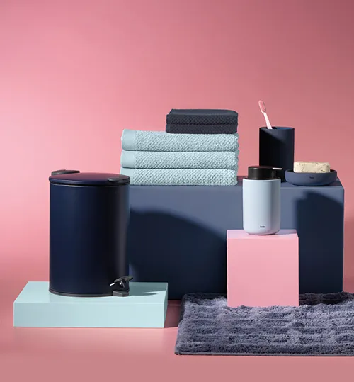 Badezimmer-Accessoires Set mit Handtüchern, Behältern und Zahnbürstenhalter in Blau, Grau und Rosa auf rosa Hintergrund