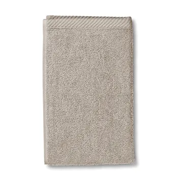 Beige Handtuch aus Baumwolle mit strukturierter Oberfläche und gewebtem Rand, gefaltet auf weißem Hintergrund.