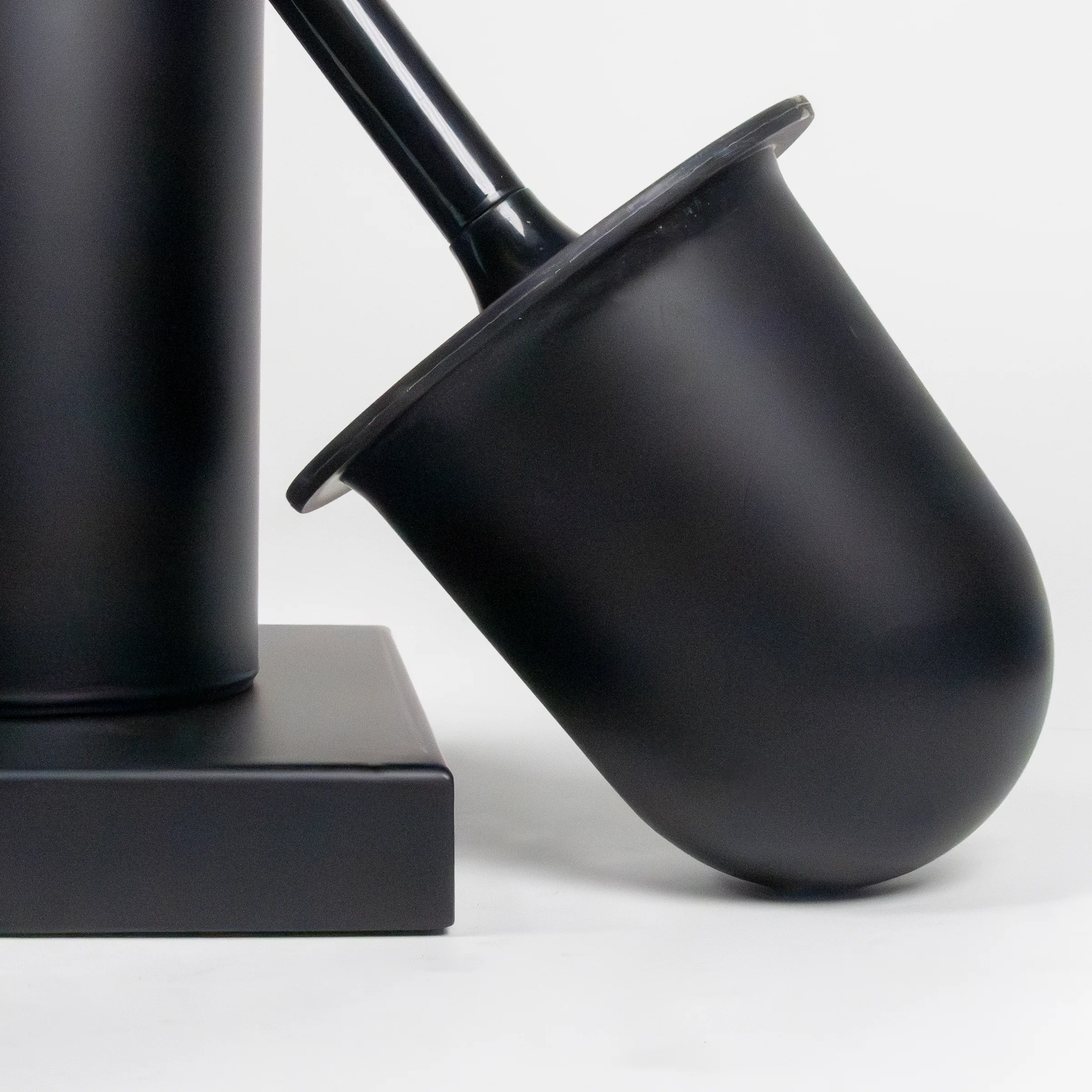 Moderne schwarze Schreibtischlampe mit verstellbarem Arm - Design Tischleuchte Schwarze moderne Schreibtischlampe mit verstellbarem Lampenschirm auf quadratischem Sockel vor hellem Hintergrund