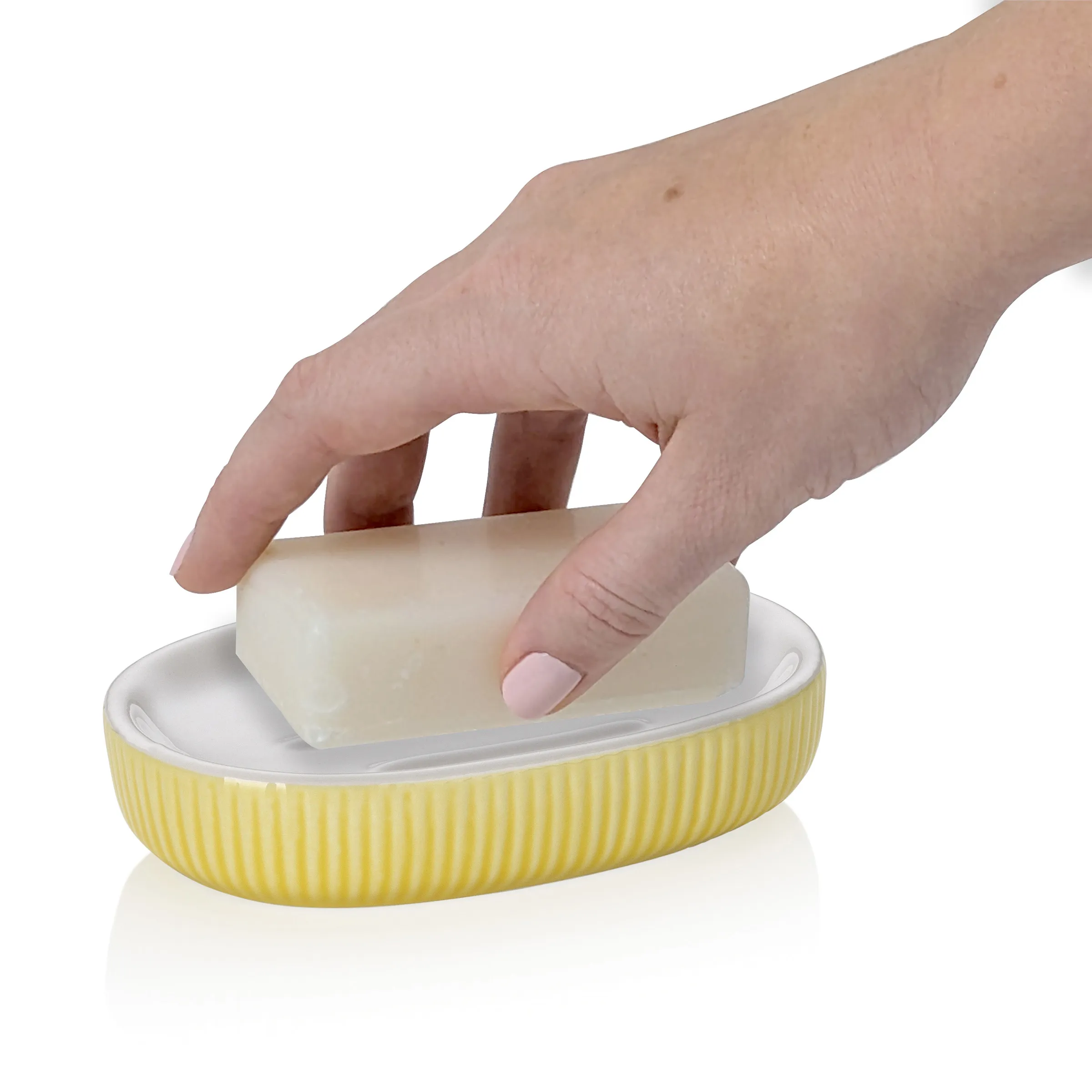 Seife und Seifenschale - Hygiene und Badezimmer Accessoires Hand nimmt ein Stück Seife aus einer gelben Seifenschale mit weißem Einsatz