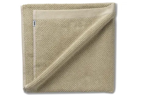 Beige strukturierte Handtuchdecke aus Baumwolle, gefaltet mit sichtbarem Label, auf weißem Hintergrund