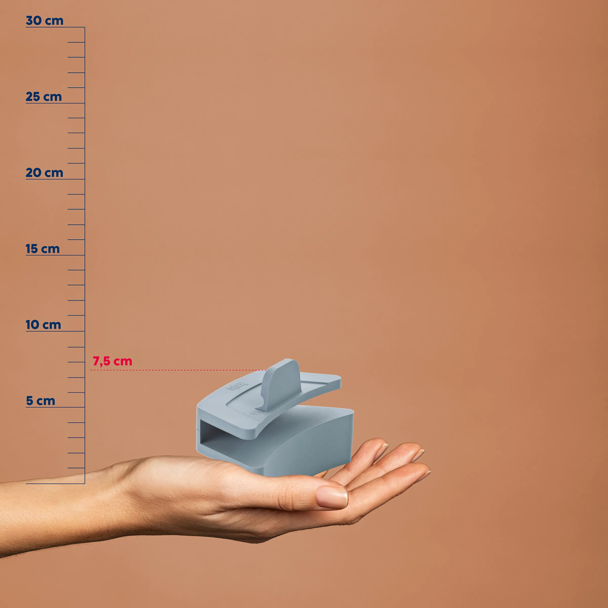 Kompaktes Stanzgerät 7,5 cm – Handliches Locher-Tool mit Größenvergleich Hand hält graues Stanzgerät vor Maßstab, Höhe 7,5 cm, auf beigem Hintergrund