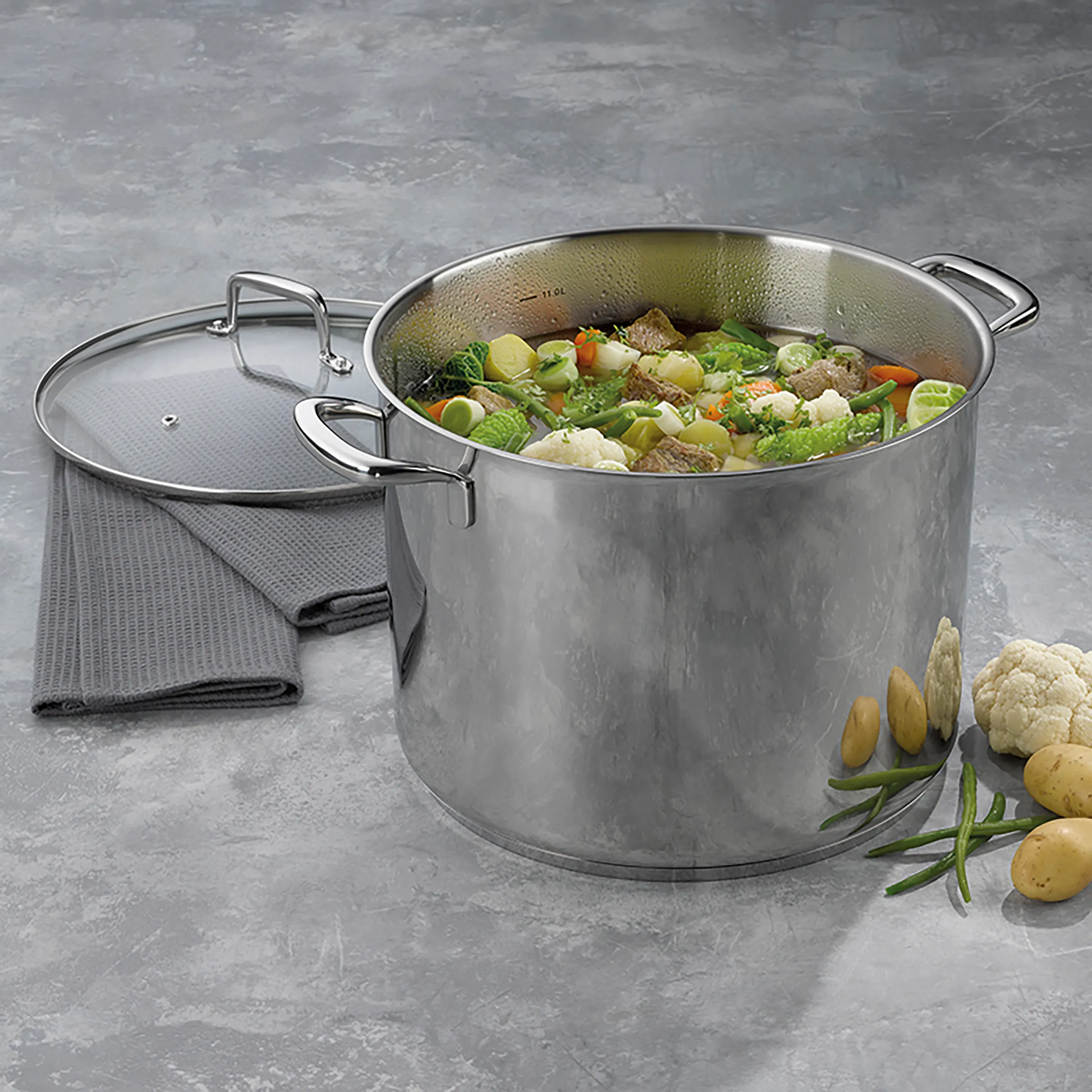 Großer Edelstahl-Suppentopf mit Eintopf-Rezept Großer Edelstahl-Suppentopf mit Deckel, gefüllt mit Gemüse-Fleisch-Eintopf, umgeben von frischen Zutaten wie Kartoffeln, Blumenkohl und Bohnen.