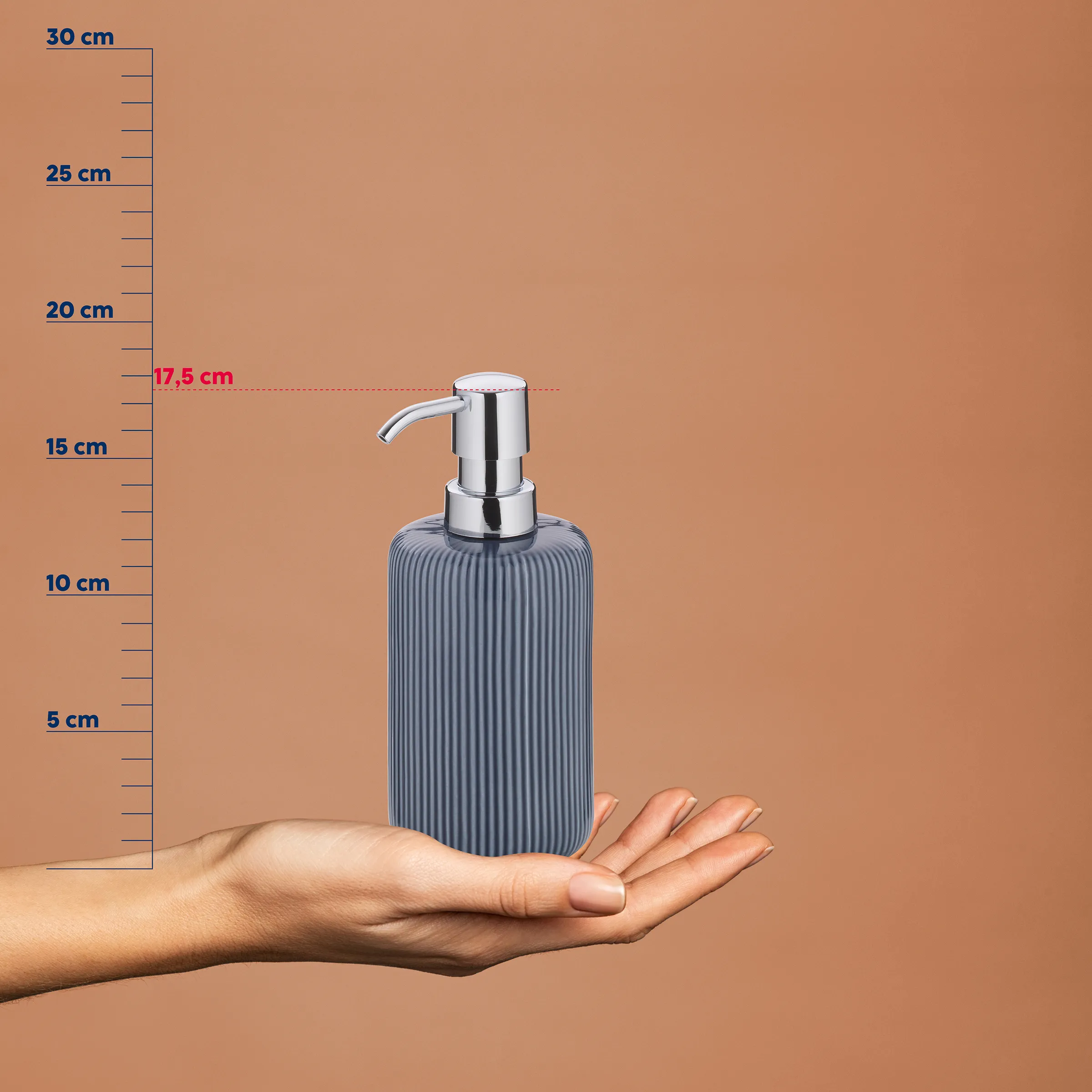 Seifenspender grau gerifft mit Chrompumpe 17,5 cm – stilvolles Badezimmer-Accessoire Grau geriffelte Seifenspender mit Chrompumpe auf Hand, Höhe 17,5 cm, vor Messskala auf beigem Hintergrund