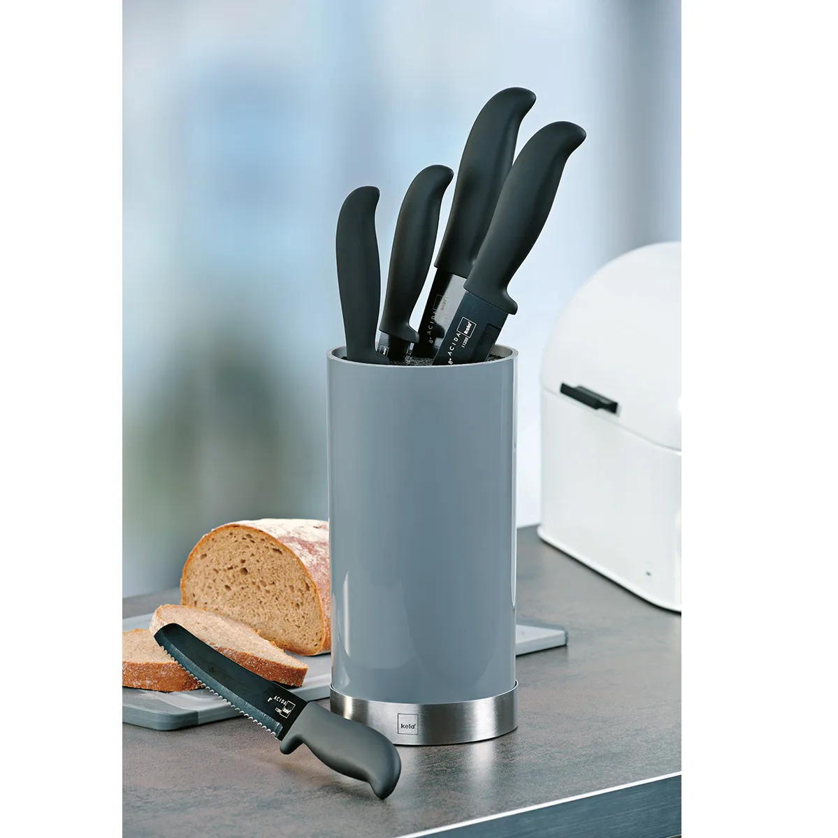 Messerblock Set mit Küchenmessern und Brotmesser Grauer Messerblock mit schwarzen Messergriffen auf Küchentheke, daneben geschnittenes Brot und schwarzes Brotmesser