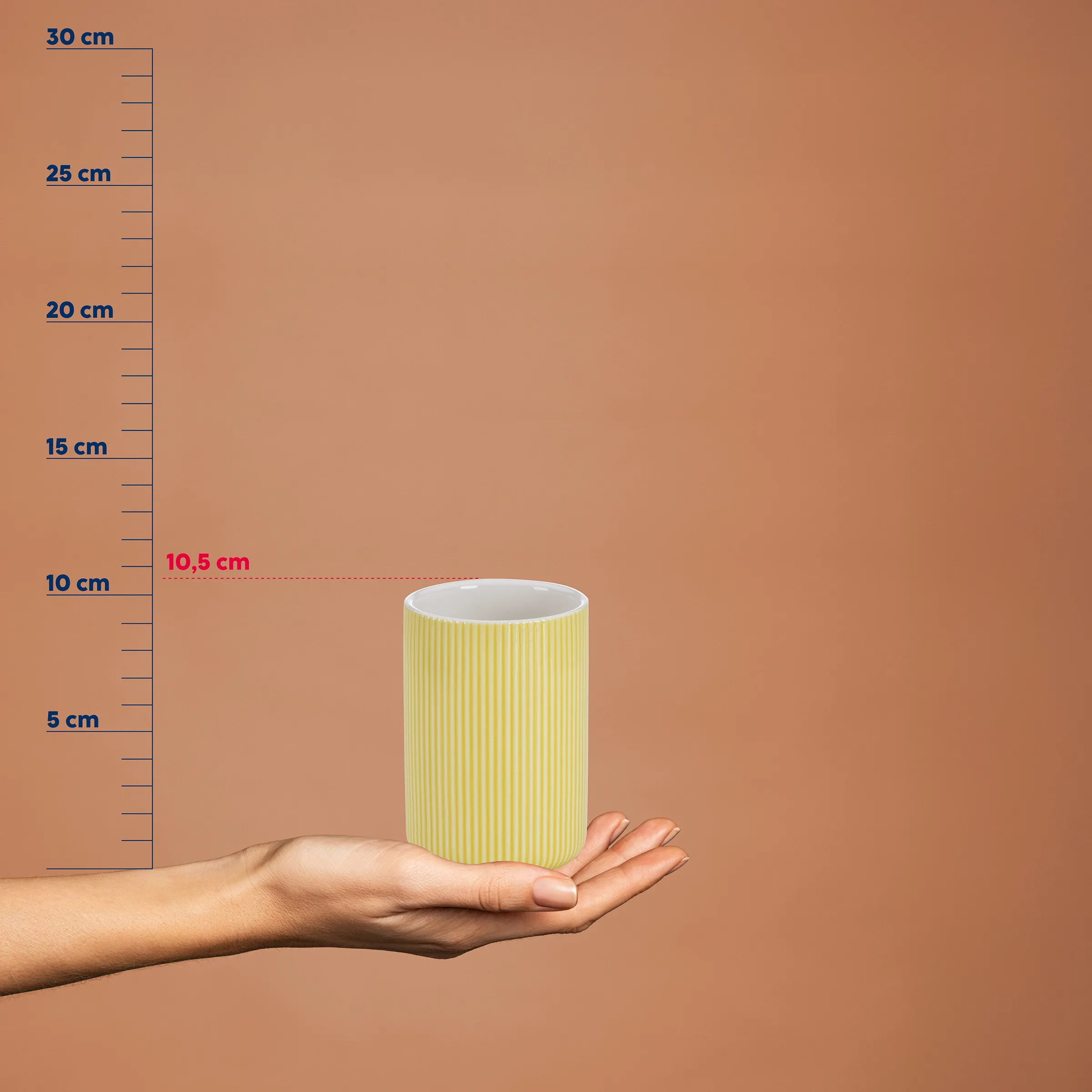 Gerillter Keramikbecher gelb-weiß 10,5 cm - Moderne Tasse mit Größenangabe Gelb-weißer Keramikbecher mit gerillter Oberfläche auf ausgestreckter Hand vor Größenskala, Höhe 10,5 cm
