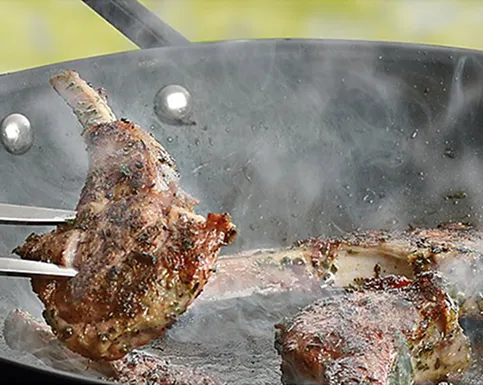 Grillpfanne Fleisch braten Rezept Zwei Fleischstücke werden in einer Grillpfanne mit Öl und Knoblauch gebraten