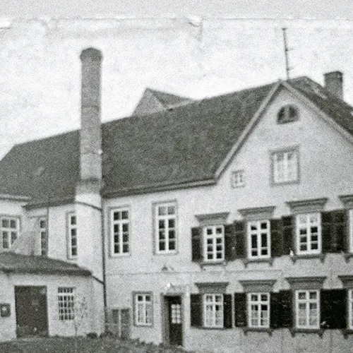 Historisches Haus mit Schornstein - Vintage Architektur Fotografie Historisches Schwarzweiß-Foto eines zweistöckigen Hauses mit großem Schornstein, grünem Satteldach und ausreichend Fenstern.