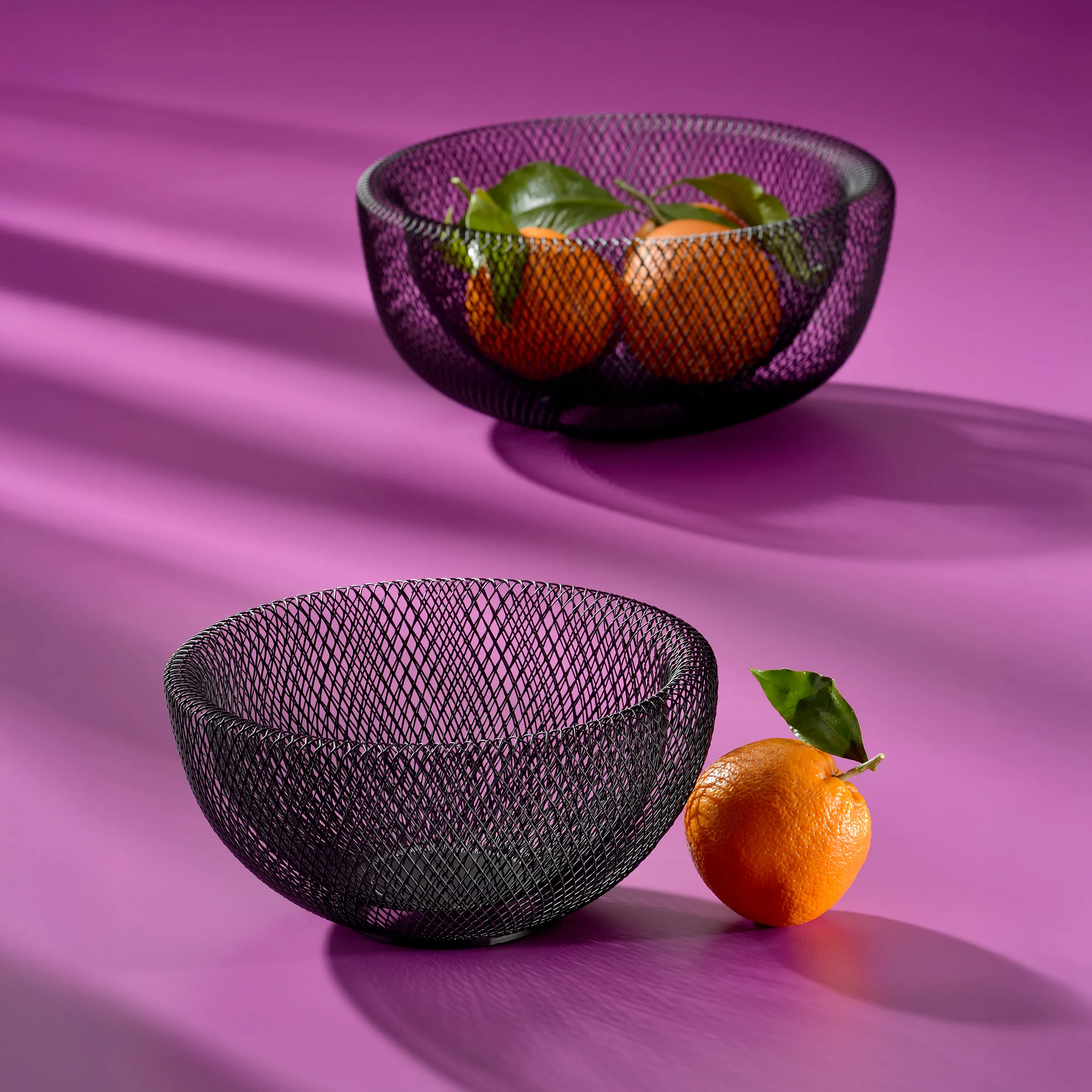 Bol à Fruits en Métal Noir - Rangement Cuisine Moderne Bol en fil métallique noir avec des oranges sur fond rose, décoration de cuisine moderne