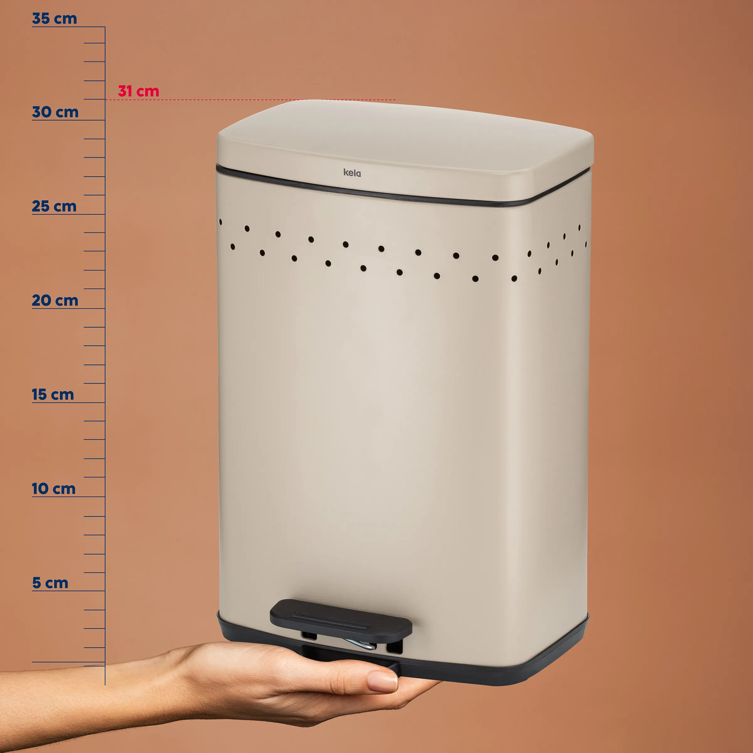 Kela Treteimer beige mit Messskala – kompakter Mülleimer 31 cm Höhe Beiger Kela Treteimer mit Messskala und Hand am Fußpedal, zeigt Höhe von 31 cm