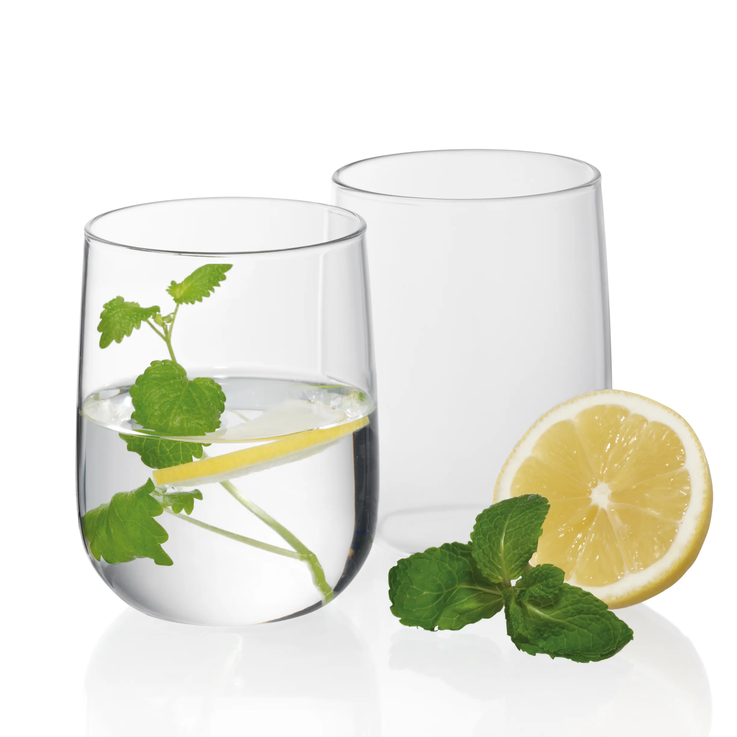 Erfrischendes Minz-Zitronenwasser - Getränk Glas mit Wasser, Minze und Zitronenscheibe neben leeren Glas und frischer Zitrone mit Minzblättern