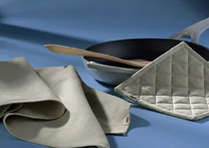 Küchentextilien Set - Geschirrtücher, Topflappen und Pfannenschutz Verschiedene Küchentextilien: Geschirrtücher, Topflappen und Pfannenschutz auf blauem Hintergrund