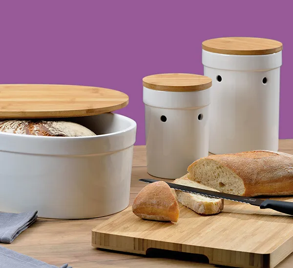 Brotdosen Set mit Bambusdeckel - Luftdurchlässige Brotaufbewahrung Weiße Brotdosen mit Bambusdeckel in drei Größen, daneben frisches Baguette auf Holzbrett