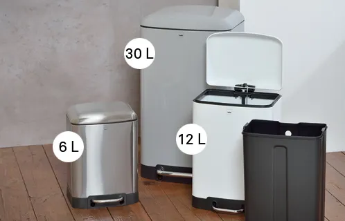 Treteimer Set verschiedene Größen Metall Kunststoff Vier Treteimer in verschiedenen Größen (6L, 12L, 30L) aus Metall und Kunststoff in Silber und Schwarz auf Holzboden.