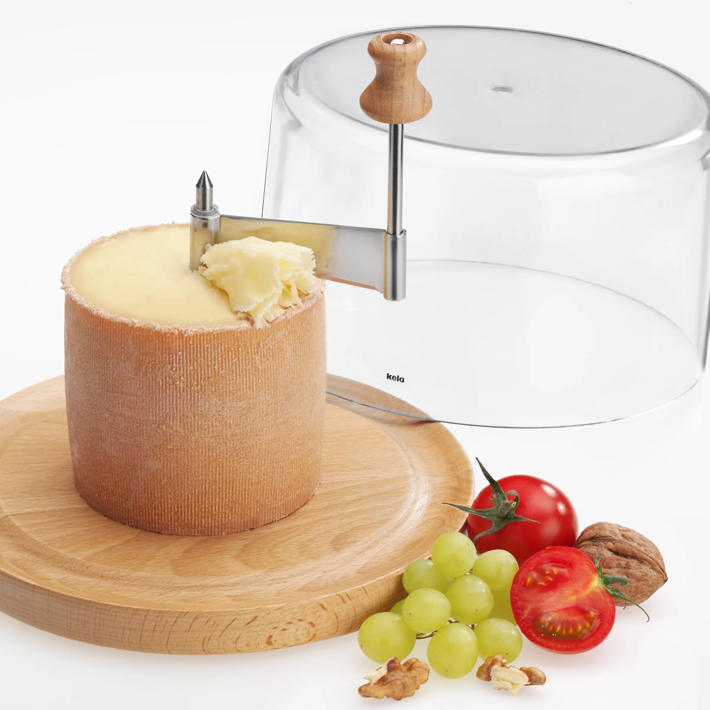 Tête de moine Käsehobel Girolle mit Käselaib und Käseröschen Tête de moine Käse mit Girolle-Hobel auf Holzbrett, daneben Trauben, Tomaten und Walnüsse