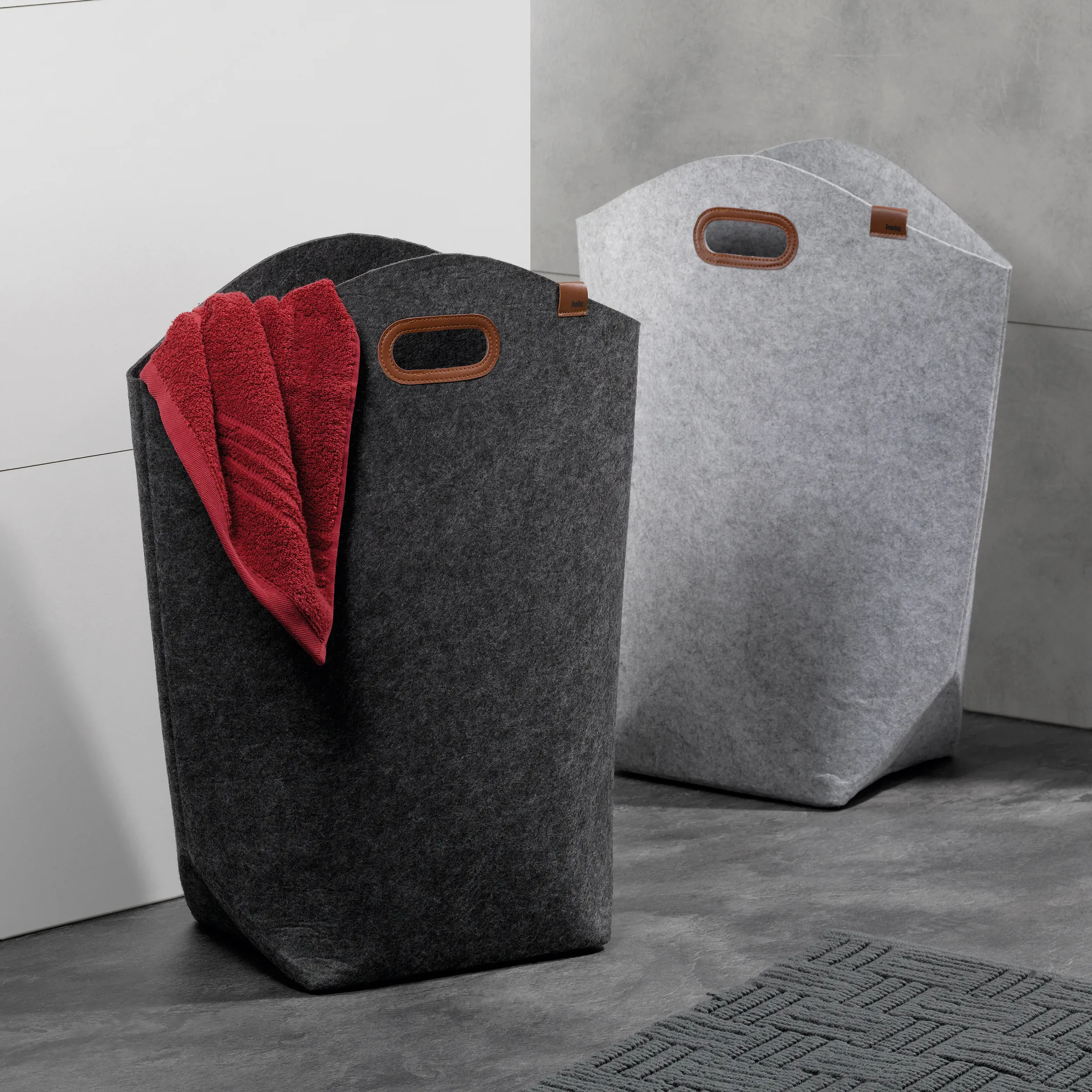 Filz-Wäschekörbe mit Ledergriff - Moderne Wäschesammler Set Zwei moderne Filz-Wäschekörbe in Dunkelgrau und Hellgrau mit braunen Ledergriffen, roter Handtuch im dunklen Korb