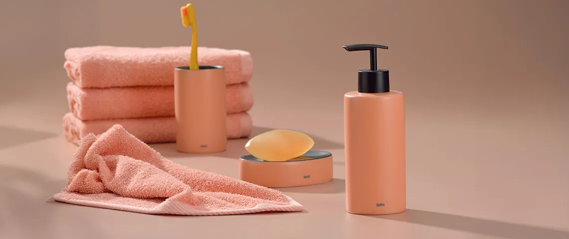 Badezimmer Accessoires Set Pfirsich kaufen Peachy-farbenes Badezimmer-Set mit gestapelten Handtüchern, Seifenspender, Zahnbürstenhalter und Seifenschale